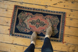Feet on antique Persian Senneh sampler rug, displaying indigo, blush design and characterful wear.