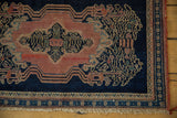 Antique Senneh rug mat corner with blush rose field, indigo vinery, secured side, and fringe.