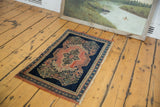 Fringed corner of the antique Persian Senneh rug showcasing indigo borders and blush rose scrolling vinery.