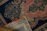 Folded antique Senneh rug showing tight beige foundation, red fringe, and worn indigo vinery.
