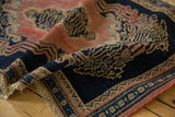 Intricate scrolling vinery on the indigo and blush border of this antique Senneh rug, with fringed end.