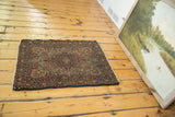 Angled detail of antique Kerman rug's cochineal red floral border and secured short fringe.