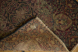 Antique Persian Kerman rug's ornate red and navy floral pile detail, revealing its hand-knotted foundation and fringe.
