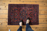 Corner of a vintage Persian Lilihan rug, showcasing the meandering vine border and raspberry field motifs.
