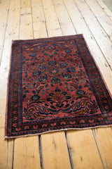 Vintage Lilihan rug's dusty raspberry red field with scrolling leaves and classic floral border.