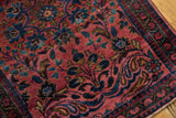 Lilihan rug corner showing dusty raspberry field, navy scrolling floral vinery, low pile.