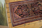 Detailed corner of a Vintage Lilihan runner with fringe and ornate borders in raspberry, blue, gold.