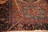 Vintage Karaja rug's navy blue border, cherry red field, geometric motifs, and white fringe.