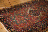 Vintage Karaja rug corner detail, cherry red field, navy geometric border, white fringe.