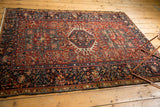 Navy blue border and cherry red field of a vintage Karaja rug, highlighting polychrome selvage.