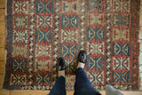 Geometric palmette motif on antique Caucasian rug with cherry red, sky blue, and visible foundation wear.