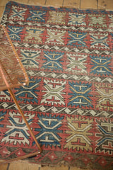 Worn geometric palmette and wave borders on antique Caucasian rug; cherry red, sky blue, beige tones.