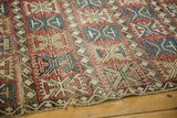 Tattered lower corner of an antique Caucasian rug, showing exposed foundation and geometric patterns.