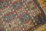 Antique Caucasian rug with geometric palmette motif in cherry red, sky blue, visible foundation, tattered edge.