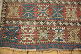 Tattered end and exposed foundation of a geometric Caucasian rug with red, blue, beige palmette motifs.