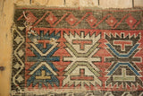 Close-up of antique Caucasian rug showing wear, visible foundation, and tattered side.
