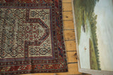 Geometric ivory, red, and navy patterns, with visible wear, on an antique Marsali Caucasian rug.
