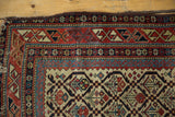 Antique Caucasian rug upper corner, with rich red, navy geometric borders and aged ivory ground.