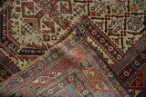 Hand-knotted foundation, geometric motifs, and threadbare wear of the antique Marsali Caucasian rug.