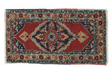Vintage Persian Heriz rug mat with a large central medallion in navy blue, red, and gold.