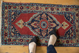 Vintage Heriz rug mat shown to scale, with a large navy medallion on a cherry red field.