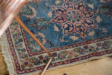 Ivory border with cochineal red and navy motifs, sky blue field, blush floral pattern, and fringe.