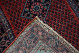 A folded corner on the vintage Engelas rug reveals its dense pile and intricate navy and ivory border.
