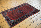 Angled perspective of a vintage Engelas rug showing its cherry red field and navy border.