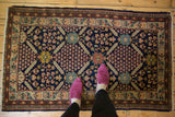 Vintage Pakistani Lahore rug corner showcasing navy lattice and sky blue, gold floral motifs.