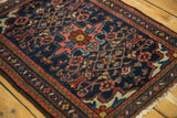 Close-up of vintage Borchalou rug's blush, navy, and brown zig-zag and vine borders.