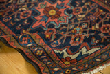 Borchalou rug corner with navy, blush, coffee brown meandering vine border and low pile.