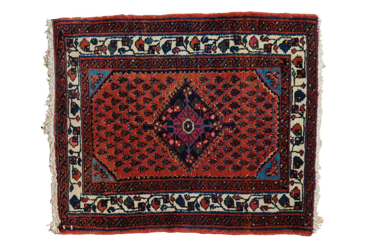 Vintage Engelas square rug with a navy diamond medallion on a rusty red field of repeating boteh patterns.