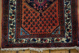 Corner detail of a vintage Persian Engelas rug showing the low pile, ivory floral border, and cotton fringe.