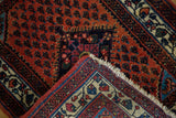 Corner of a vintage Engelas rug folded to show its hand-knotted pile and detailed ivory border.