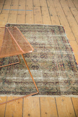 Antique Persian Kerman rug's worn field with threadbare areas and sprawling floral vinery.