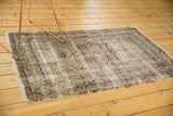 Antique Kerman rug corner showing sprawling vinery border and threadbare fringe.
