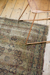 Antique Kerman rug with substantial threadbare wear and tattered perimeter edge.