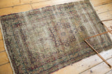 Detail of antique Kerman rug, showing threadbare field, worn vinery border, tattered edge.