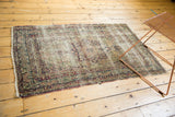 Antique Kerman rug, faded ivory field, cochineal red and navy floral medallion, worn, tattered edges.