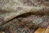 Antique Kerman rug close-up, revealing storied wear, navy, and cochineal floral vinery.