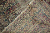 Hard wear, threadbare regions, tattered edge, and exposed foundation of an antique Kerman rug.