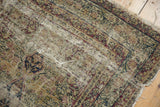 Antique Kerman rug detail showing considerable pile loss, exposed foundation, and tattered perimeter.