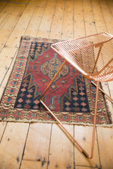 Vintage Malayer rug corner detail showing cherry red field, serrated navy border, and fringed edge.