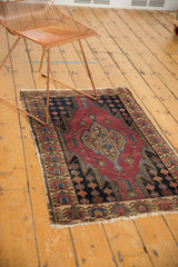 Malayer rug corner: cherry red field, serrated design, floral border, tattered end, faint foundation.