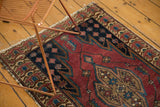 Vintage Malayer rug: cherry red field, sharply serrated blue medallion, germinating floral border.