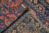 Corner of vintage Lilihan rug with faded raspberry, navy floral patterns and fraying.