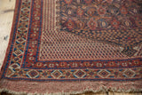 Antique Afshar rug corner featuring worn madder root red fringe and geometric border.
