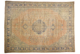 Distressed Oushak carpet featuring a faded blush roundel medallion and blue floral vinery.