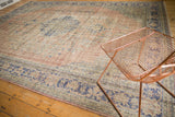 Distressed vintage Oushak rug featuring blush and cobalt blue geometric vinery border.