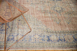 Distressed vintage Oushak carpet detail showing pale blush, cobalt blue geometric vinery.
